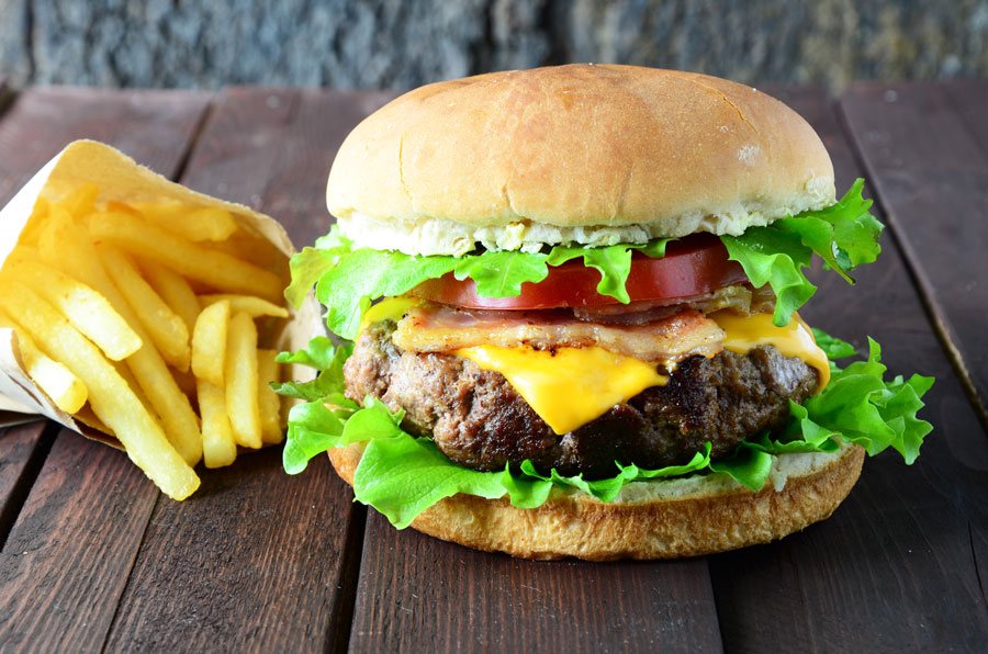 Cheeseburger with bacon, lettuce, and tomato, and a side of fries.