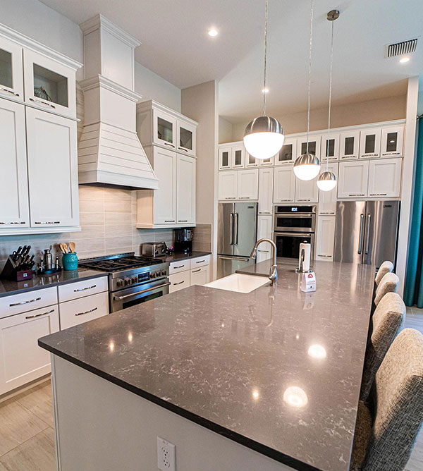 Furnished kitchen with island sink and countertop barstool seating inside a Bear’s Den Resort Orlando vacation home.