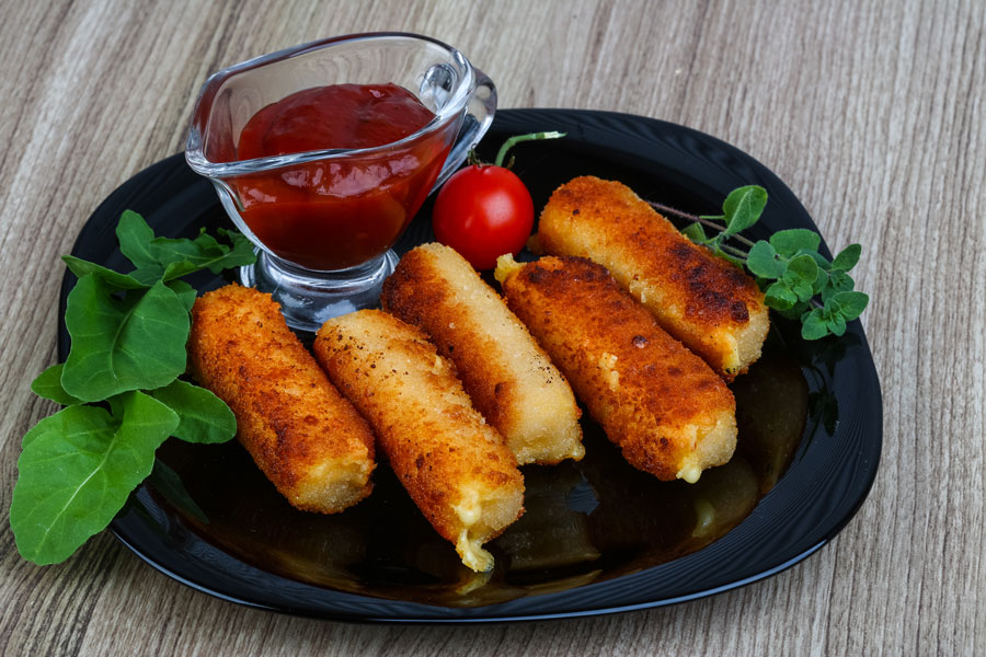 Fried mozarella sticks with a side of dipping sauce.