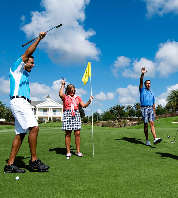 3 people cheer after sinking a golf ball on the putting green at Reunion Resort.