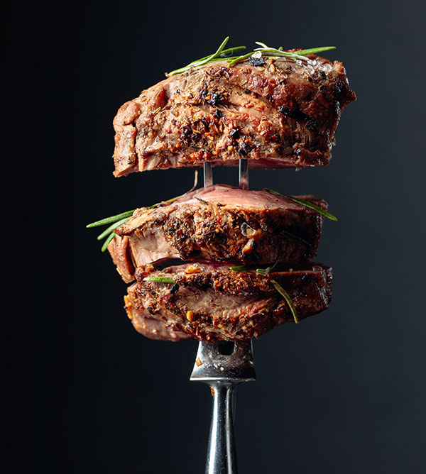 Garnished cut steak displayed on a fork.