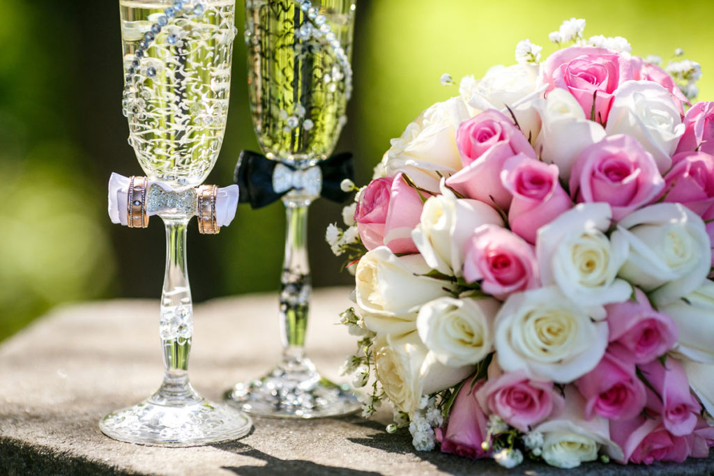 Ramo de novia y clases de champagne decoradas con alianzas.