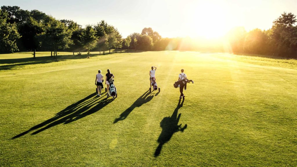 Group Of Golfers Walking On A Golf Course At Bear's Den Resort Orlando At Sunrise.