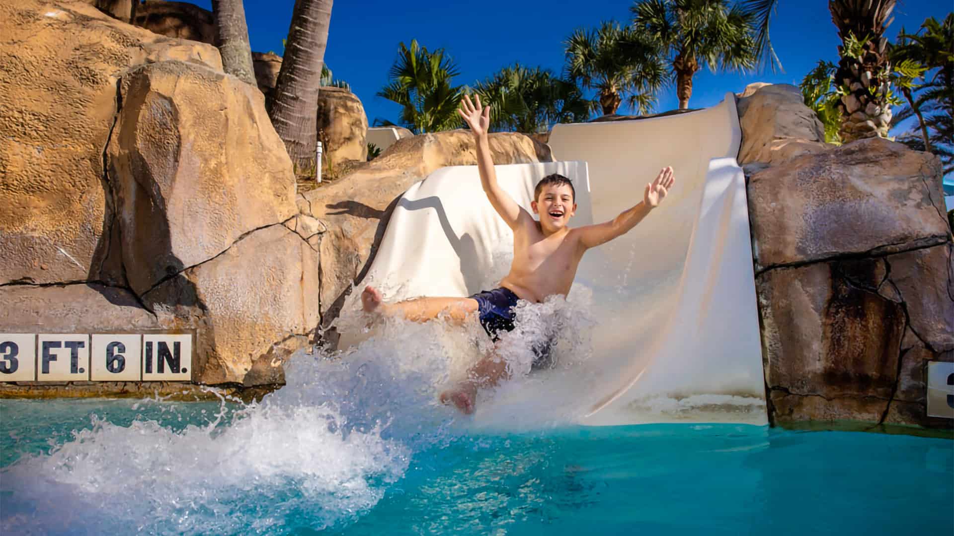 Parque acuático Bear's Den Resort Orlando: un niño sonríe mientras se desliza por un tobogán de agua.