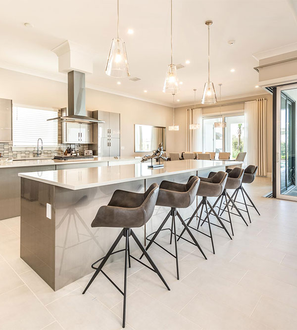 Furnished kitchen with countertop seating, dining room, and sliding glass door access to backyard pool and lanai in an 8-bedroom Bear’s Den home.