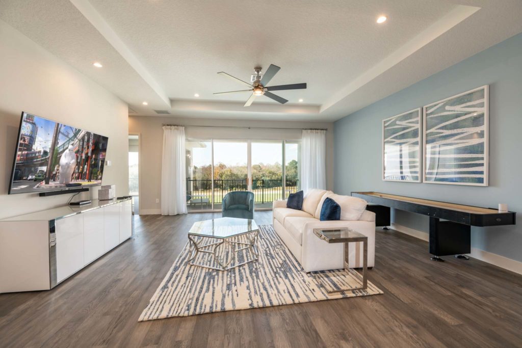 Loft with shuffleboard table, couch, TV, and balcony access in an elegant 8-bedroom Bear’s Den Resort Orlando residence.