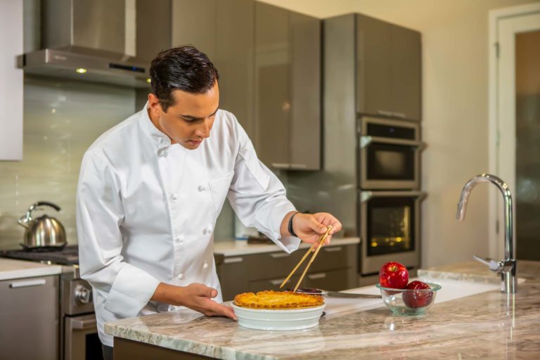 Un chef experto prepara una comida durante una experiencia de chef en el hogar.