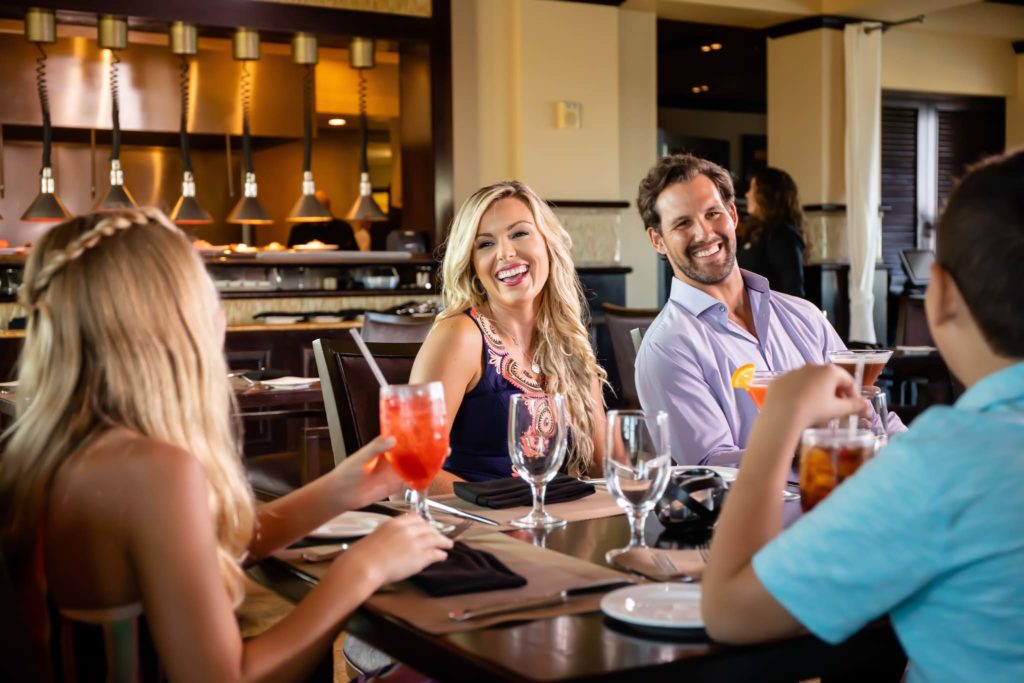 Two couples laughing and talking together while dining at Traditions Restaurant.