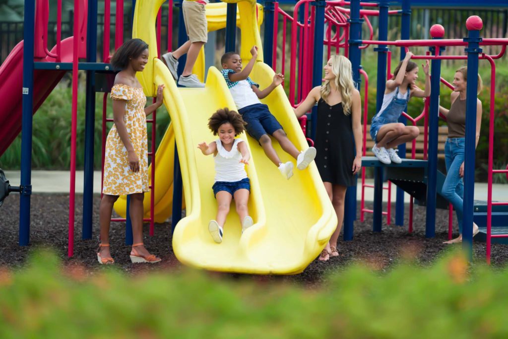 Niños deslizándose por toboganes mientras juegan con sus mamás en Golden Bear Park.