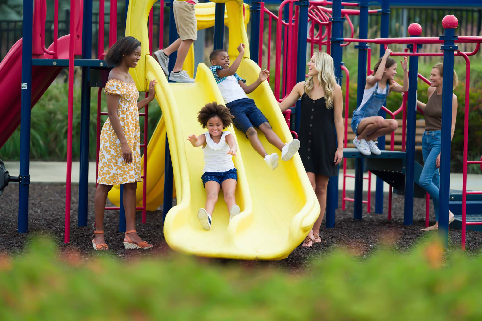 Kids sliding down slides while playing with their moms at Golden Bear Park.