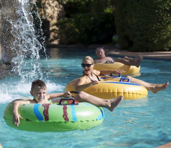 People riding on pool floats along the lazy river.