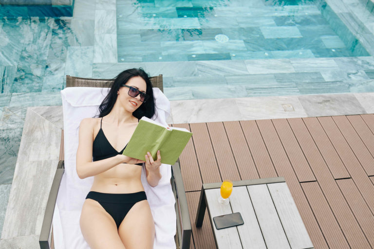 Woman Reading A Book By The Pool At Bear's Den Resort Orlando.