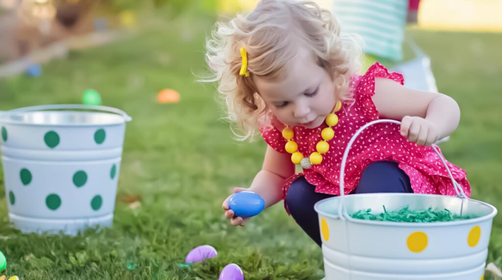 Little girl picking up eggs in an Easter Egg hunt