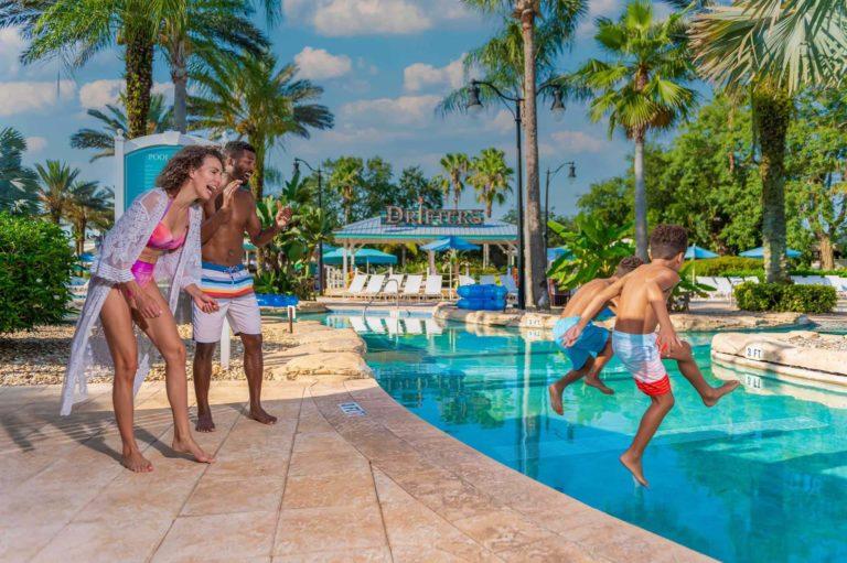 Padres riendo mientras sus hijos saltan a la piscina del parque acuático | Bear´s Den Resort Orlando