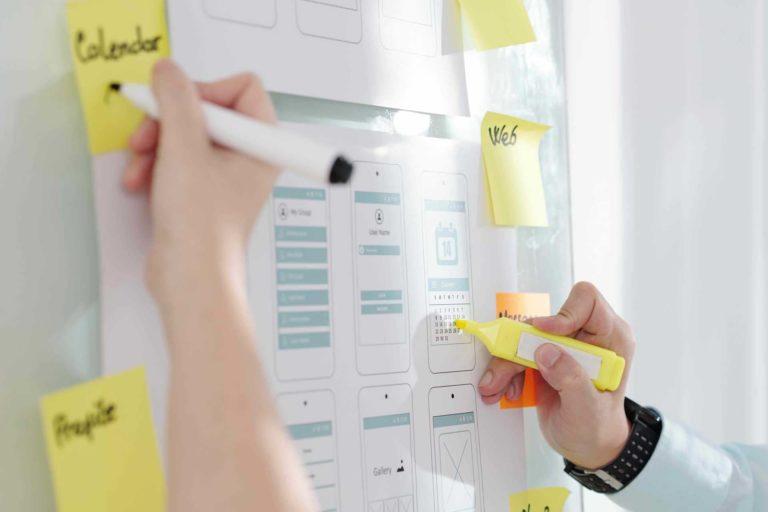 Person highlighting a deadline on a pinned wireframe mockup