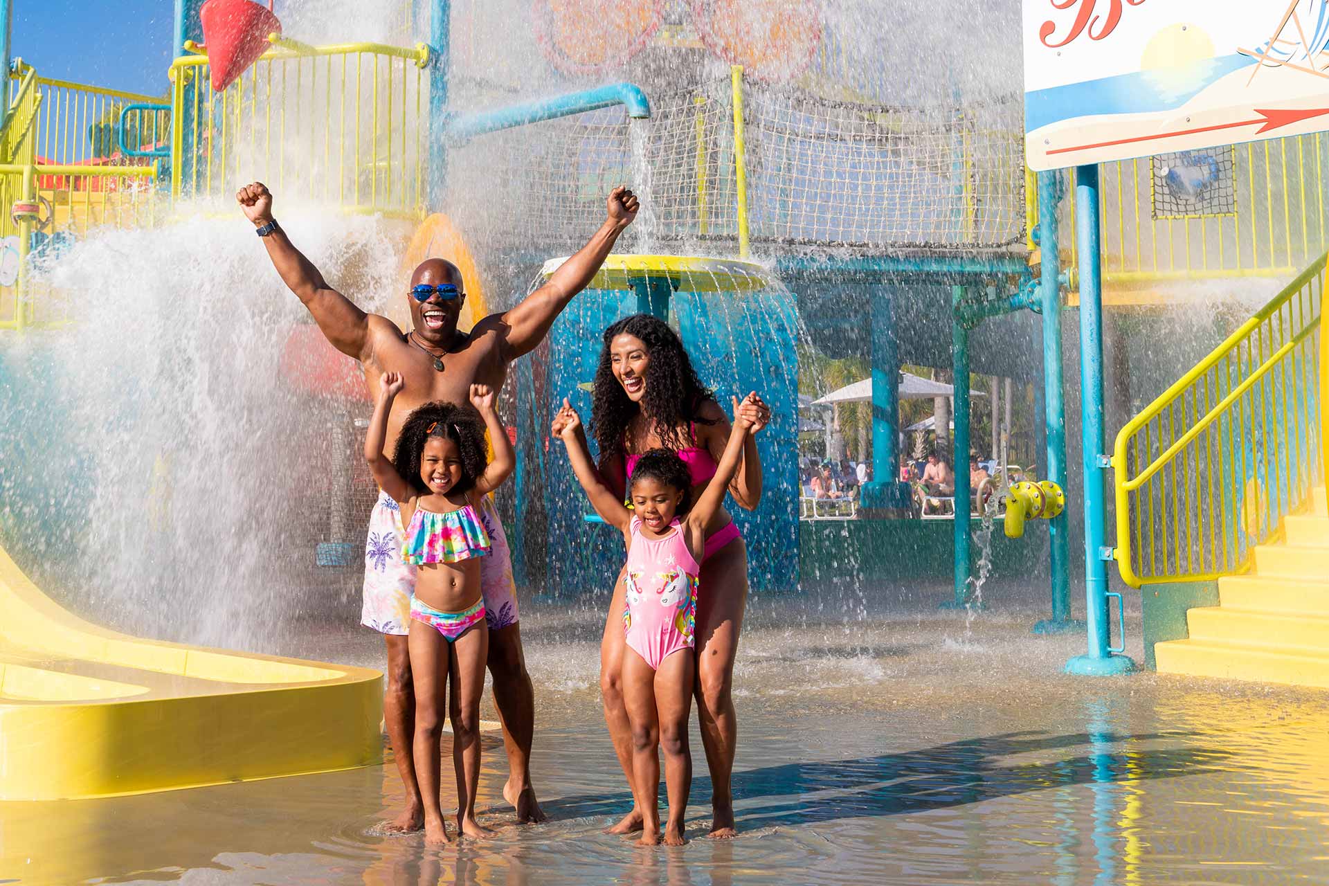 Happy family of four getting splashed by the bucket at the Encore Resort water park
