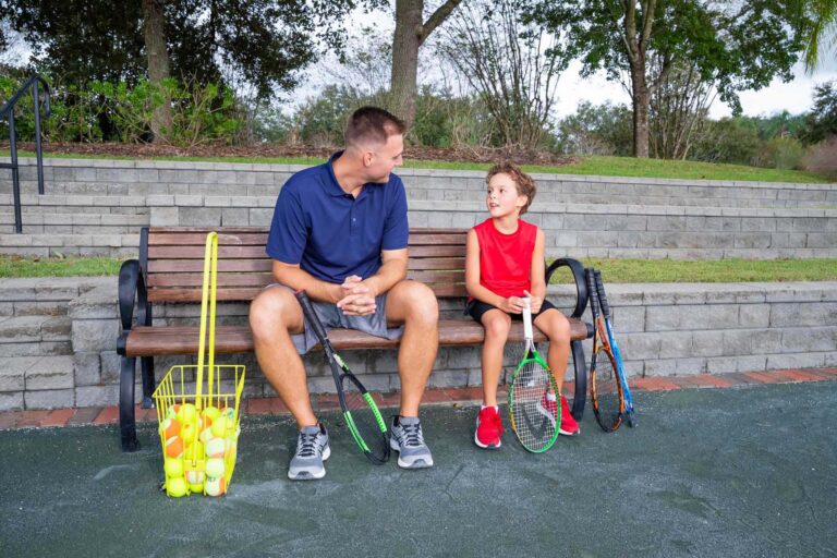 Father and son resting on a bench after playing tennis