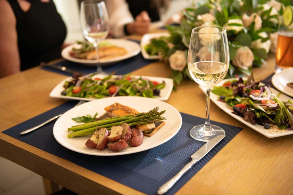 Plated salmon entree on a placemat next to a glass of wine | Bear's Den Chef Experience