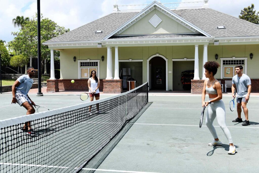 Grupo de amigos jugando dobles de tenis en Reunion Resort