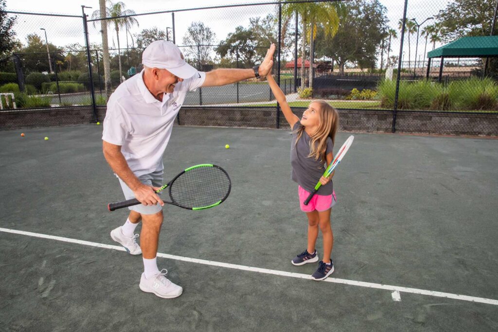 Girl high-fiving her tennis instructor at the Reunion Resort tennis courts