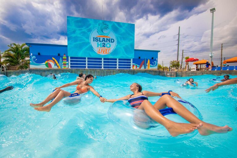 Two friends floating in tubes while holding hands in the Island H2O Water Park wave pool