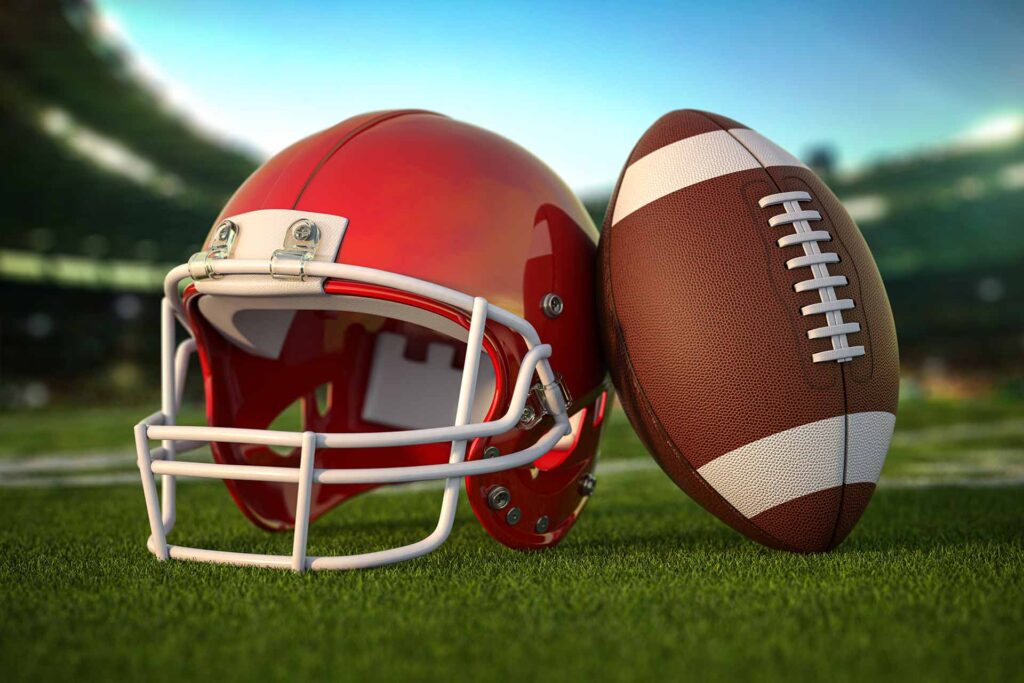 American football and helmet on a field inside a stadium