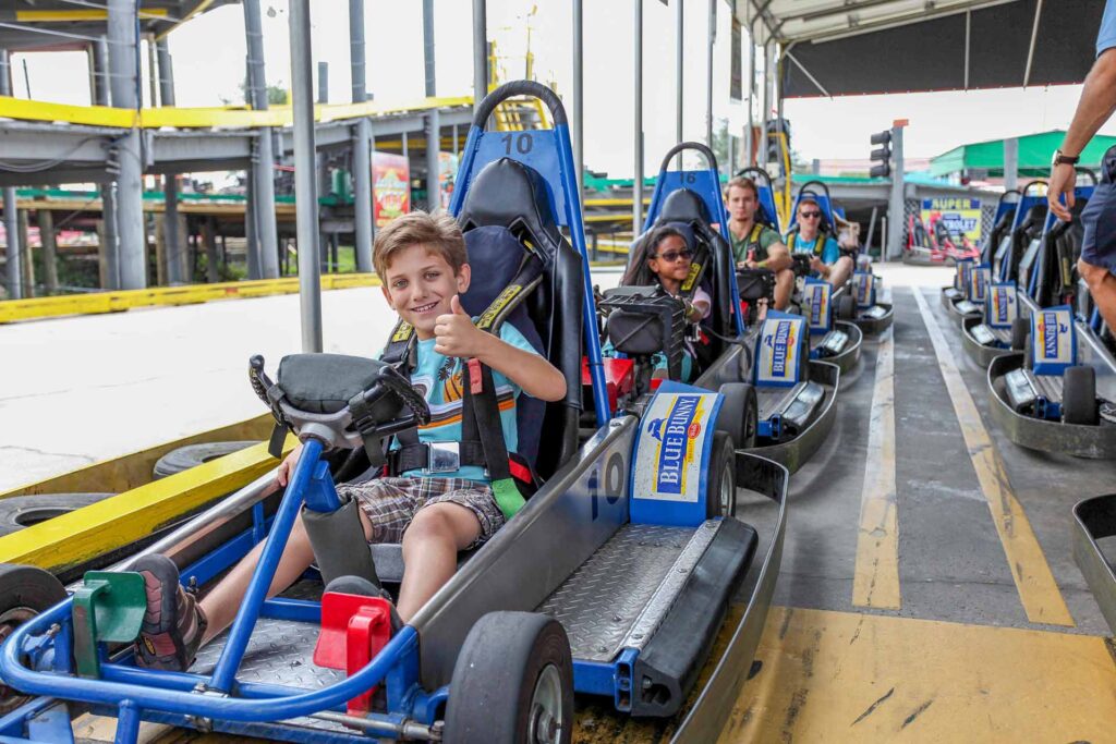 Young boy giving a thumbs up while riding a go kart at Fun Spot America in Orlando, Florida