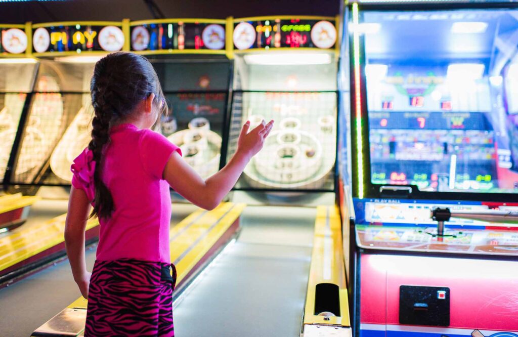 Young girl playing Skee Ball at an arcade